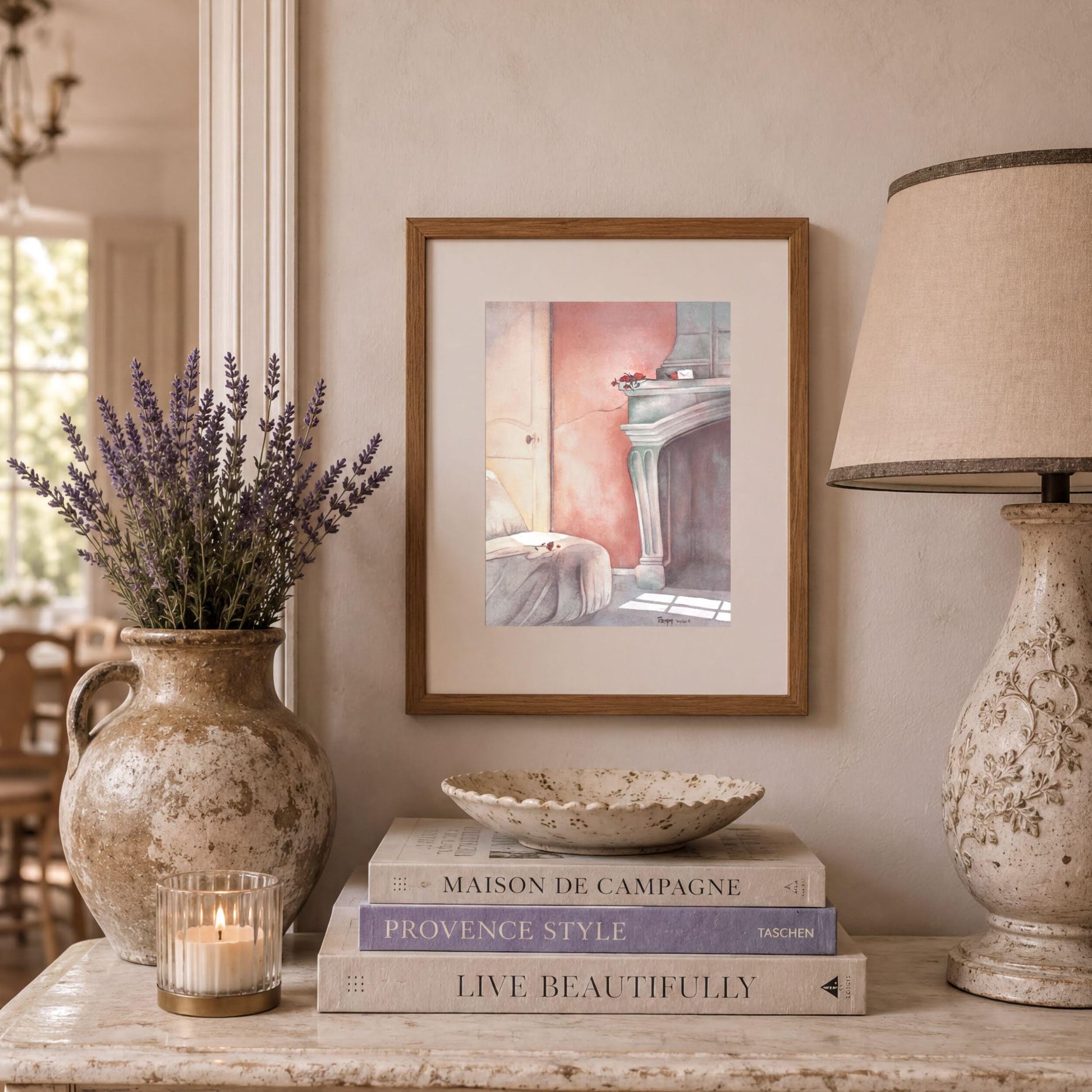 a cozy and well-decorated living space with a framed painting of a fireplace, a vase of lavender flowers, a stack of books, and a lamp on a table.
