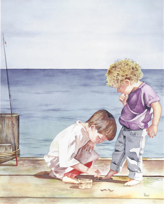 Two young boys are playing on a wooden dock, with one boy kneeling down and the other standing beside him.