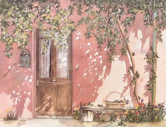a charming pink building with a wooden door, surrounded by lush greenery and vibrant flowers. A bench is situated in front of the building, inviting passersby to sit and enjoy the serene atmosphere.